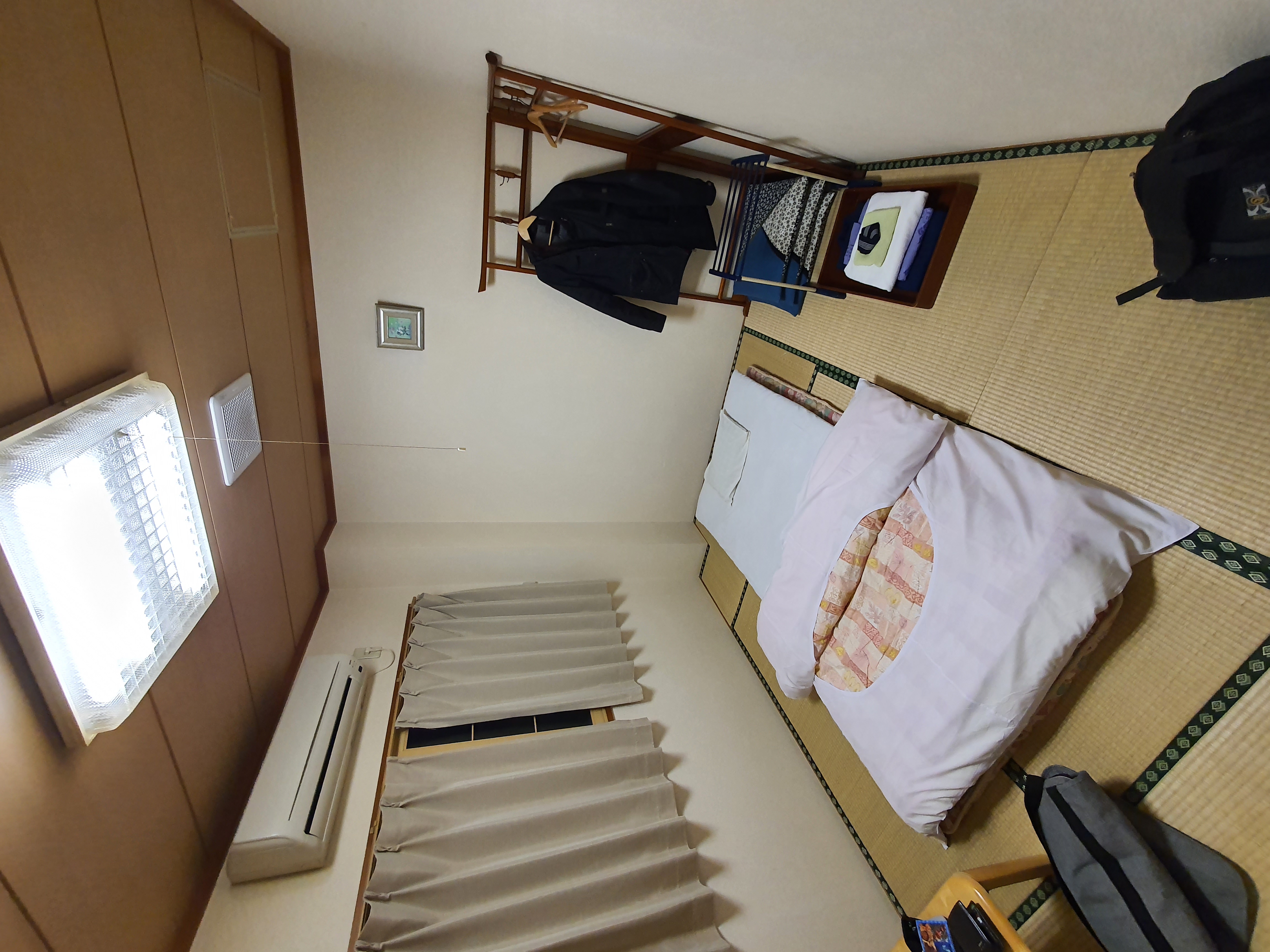 Phòng trọ truyền thống Nhật Bản với chiếu tatami, nệm futon xếp gọn gàng và chiếc bàn thấp.